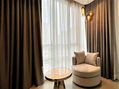 Luxurious corner seating area with elegant drapes and modern lighting in a high-rise apartment.