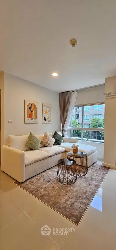 Modern living room with cozy sofa, stylish decor, and large window offering natural light and city view.