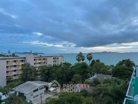 Stunning ocean view from a high-rise apartment overlooking lush greenery and city skyline.