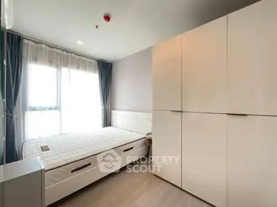 Modern bedroom with large window and sleek white wardrobe in a stylish apartment.