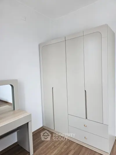 Modern bedroom with sleek wardrobe and stylish vanity on wooden flooring.