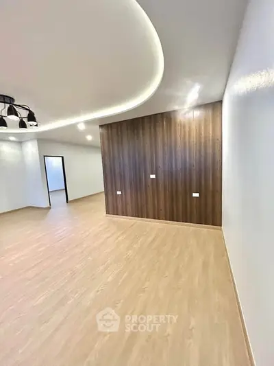 Spacious modern living room with elegant wood paneling and sleek lighting