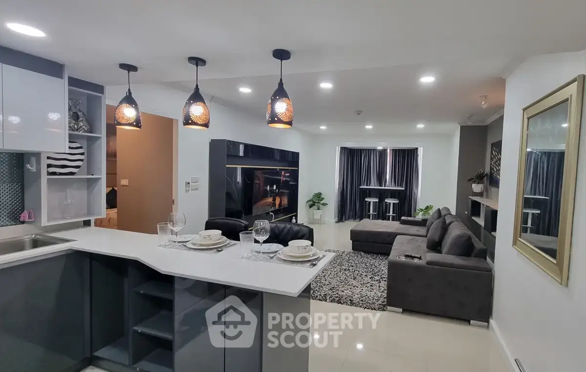Modern open-layout kitchen and living room with stylish lighting and cozy seating area.