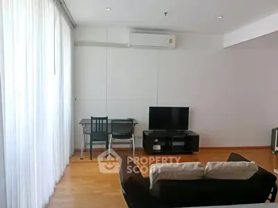 Modern living room with wooden flooring, cozy sofa, TV, and study desk under natural light.