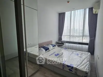 Modern bedroom with large window and mirrored closet in a high-rise apartment.