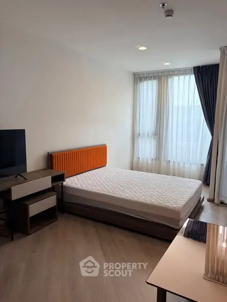 Modern bedroom with large window and stylish furniture in a bright apartment.