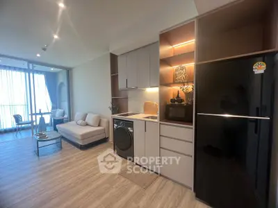 Modern living room with open kitchen, featuring sleek appliances and stylish decor, perfect for urban living.