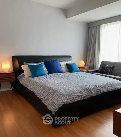 Spacious bedroom with modern decor and large windows for natural light.