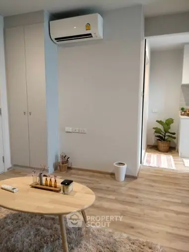 Cozy living room with modern air conditioning, wooden flooring, and a touch of greenery for a serene living experience.