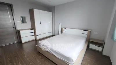 Spacious modern bedroom with sleek wooden flooring and minimalist furniture design.