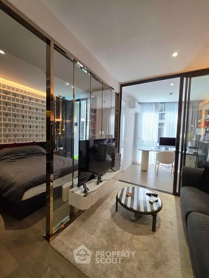 Modern apartment interior with stylish living room and cozy bedroom separated by glass wall.