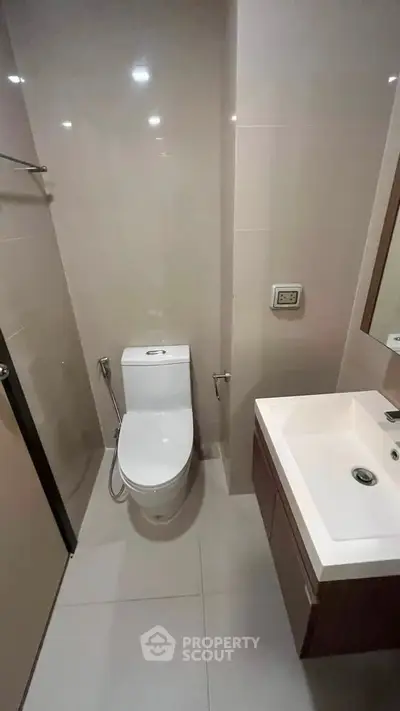 Modern bathroom with sleek fixtures and neutral tones, featuring a compact layout and contemporary design.