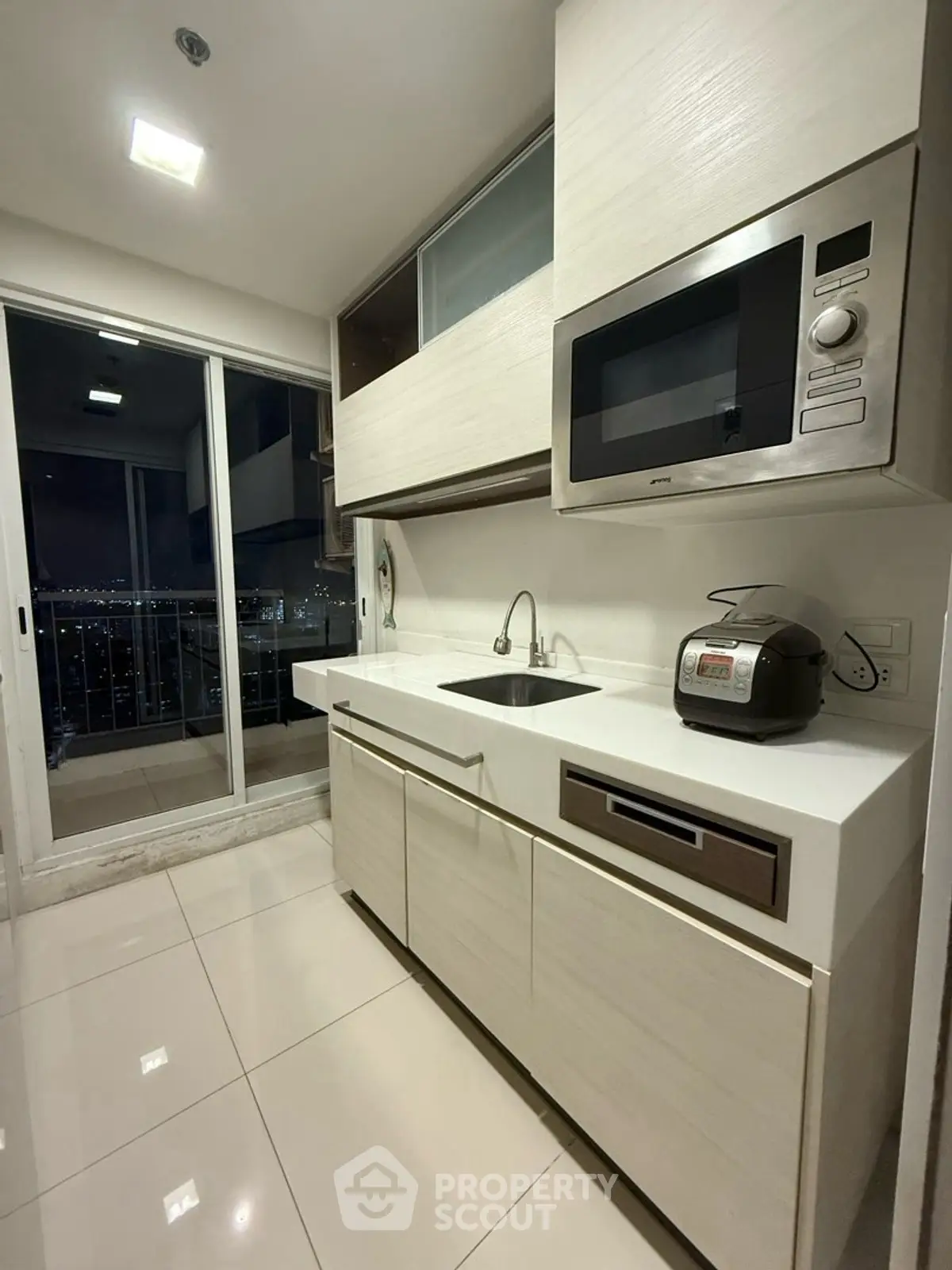 Modern kitchen with sleek cabinetry and balcony view
