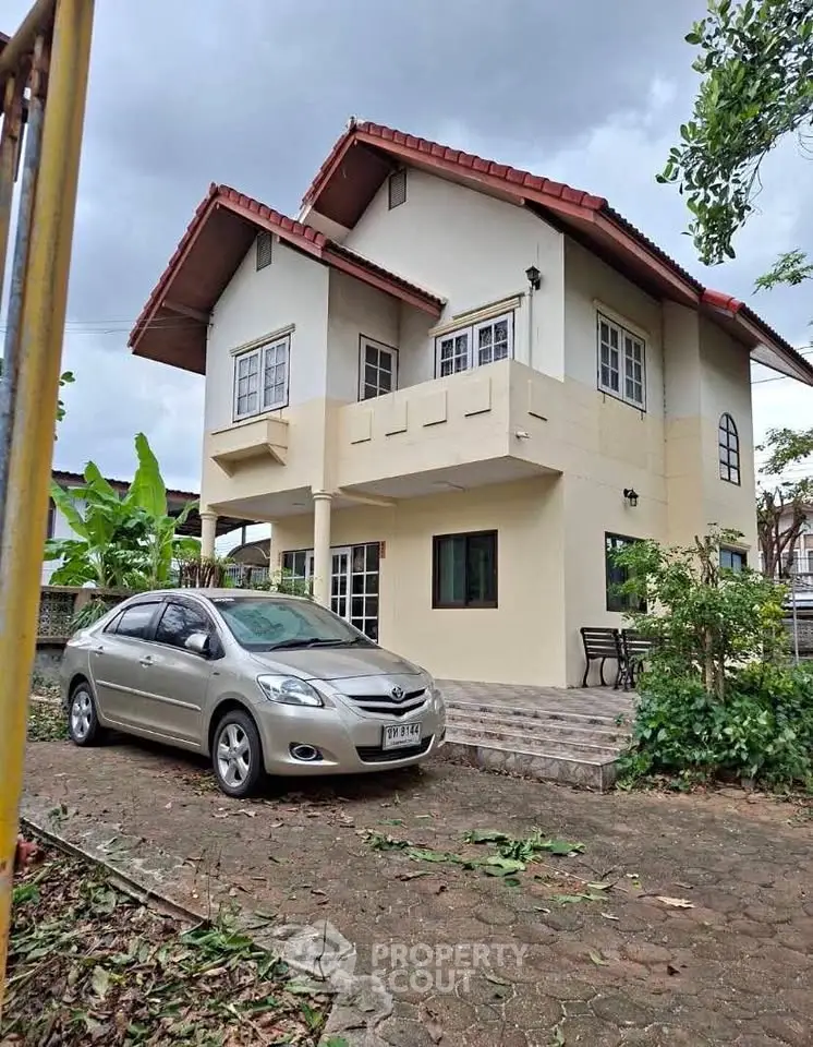 Charming two-story house with red roof and spacious driveway, perfect for family living.