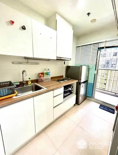 Modern kitchen with sleek cabinets and balcony view in urban apartment