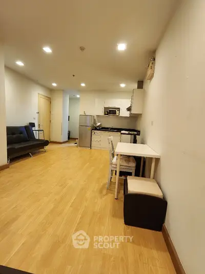 Modern open-plan living room with kitchen, featuring sleek furniture and wooden flooring.