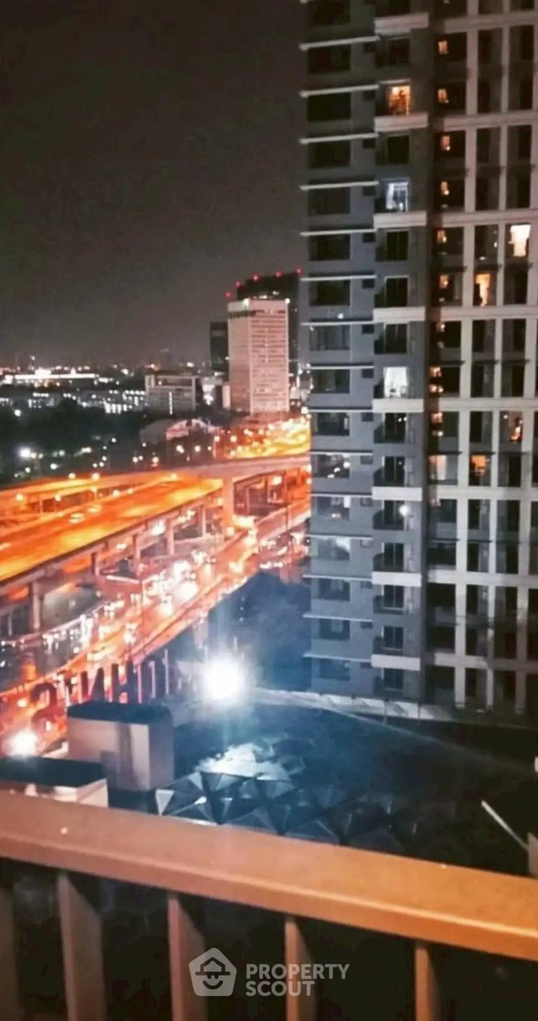 Stunning night view from a high-rise balcony overlooking city lights and highways.