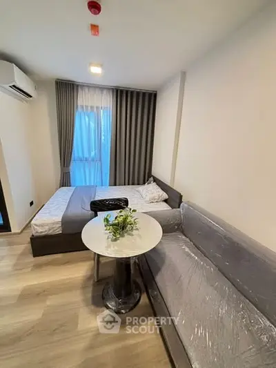 Modern studio apartment with cozy bed and stylish sofa in a compact living space.