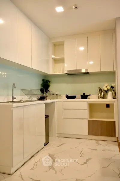 Modern kitchen with sleek white cabinets and marble flooring in a stylish apartment.