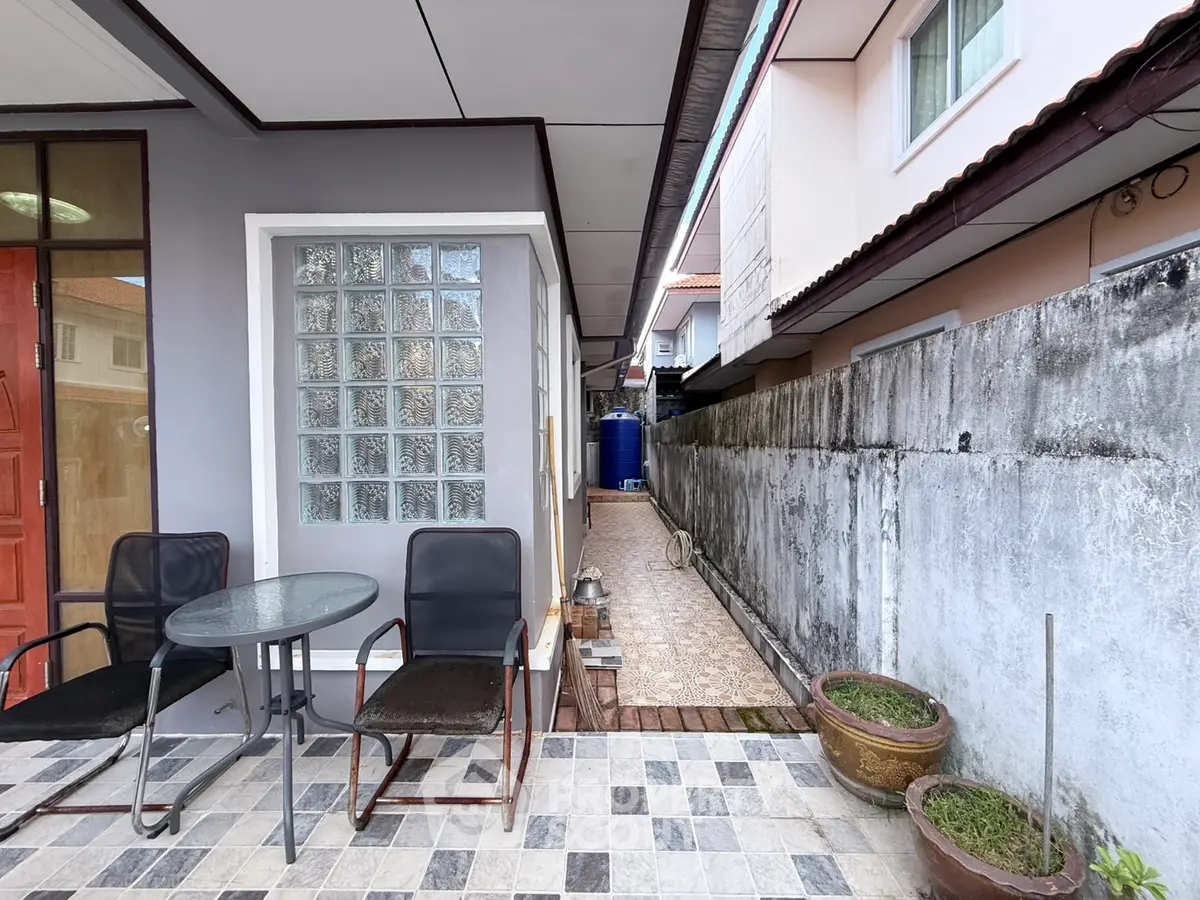 Charming outdoor patio with seating area and tiled pathway in a cozy residential setting.