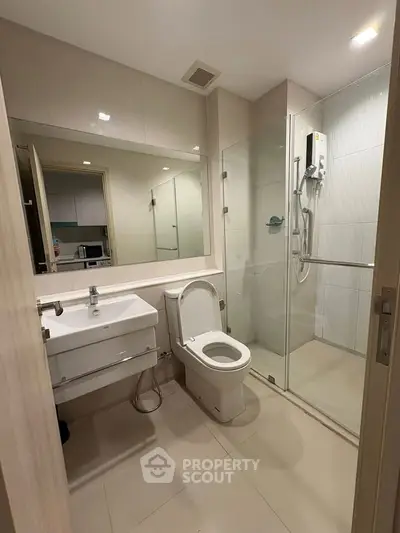 Modern bathroom with glass shower and sleek fixtures in contemporary apartment.