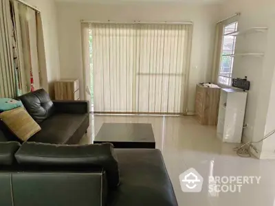 Spacious living room with modern black leather sofa and large window blinds