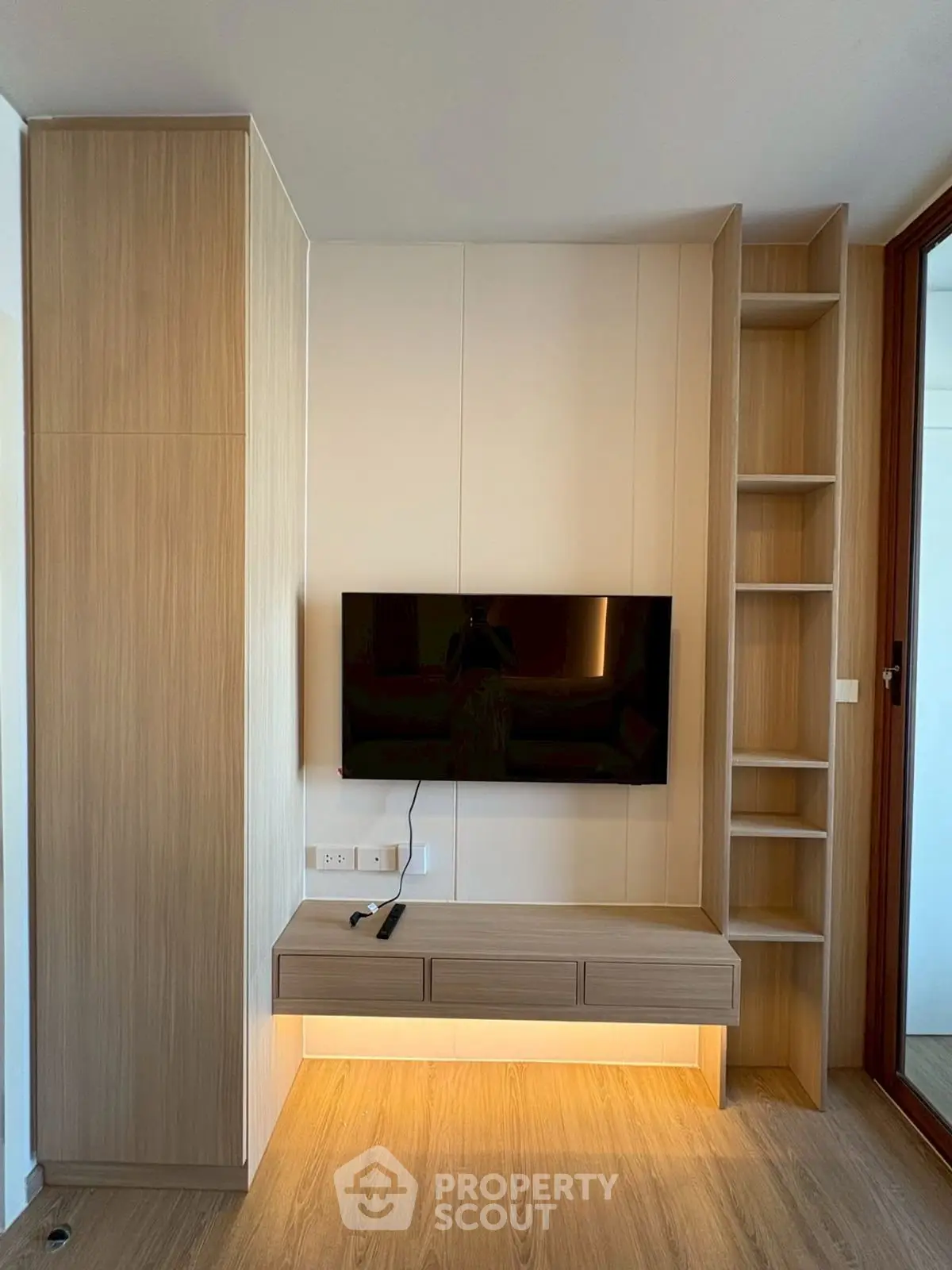 Modern living room with built-in wooden TV unit and shelves, showcasing sleek design and ample storage.