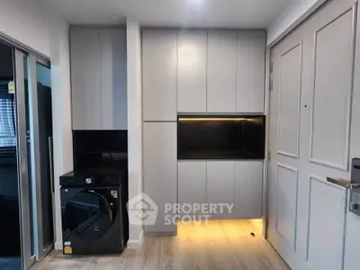 Modern laundry area with sleek cabinetry and washing machine in stylish apartment.
