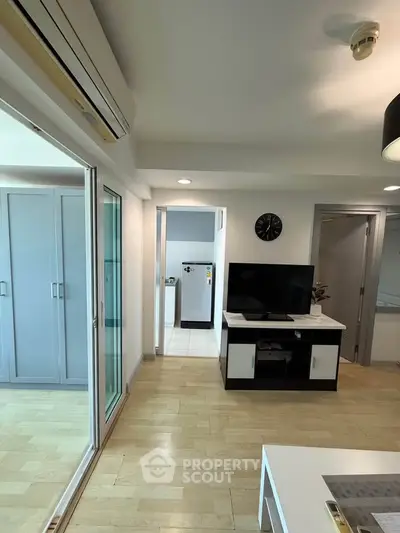 Modern living room with TV, air conditioning, and sleek wooden flooring