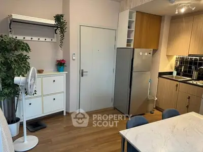 Modern kitchen with sleek cabinets, stainless steel fridge, and elegant dining area in cozy apartment.