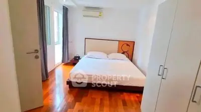 Spacious bedroom with wooden flooring and modern furnishings