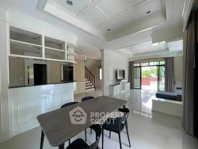 Spacious modern living room with open layout and elegant dining area, featuring large windows and stylish decor.