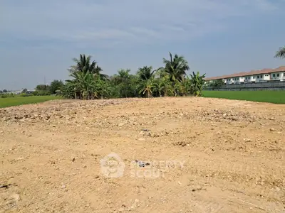 Expansive plot of land with potential for development, surrounded by lush greenery and residential area.