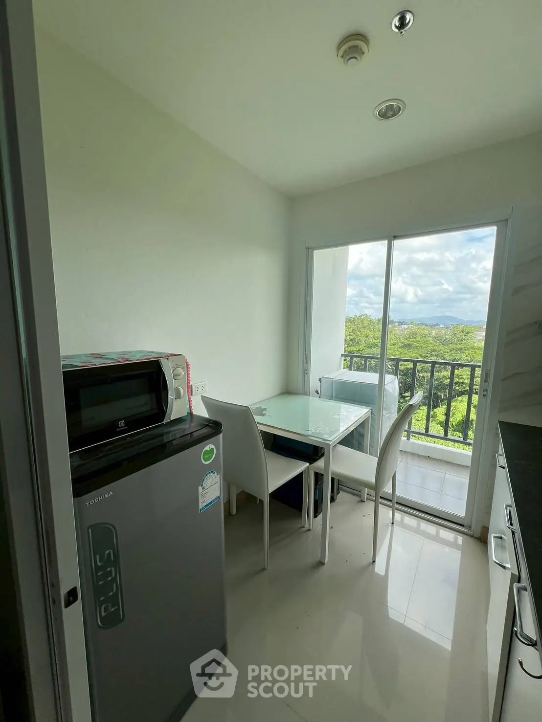 Modern kitchen with balcony view, featuring sleek appliances and dining area, perfect for urban living.