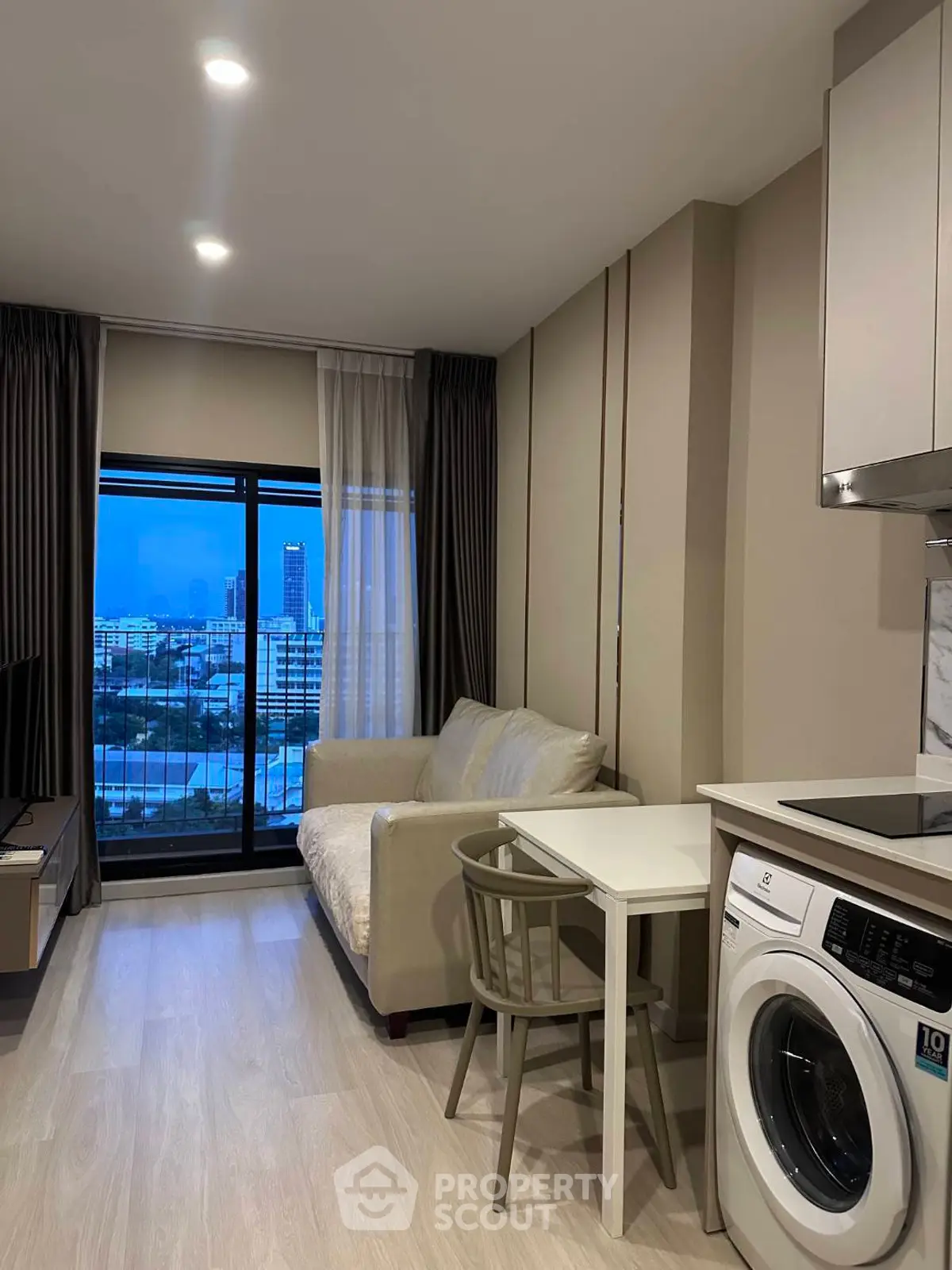 Modern living room with city view, cozy sofa, and in-unit washing machine in a stylish apartment.