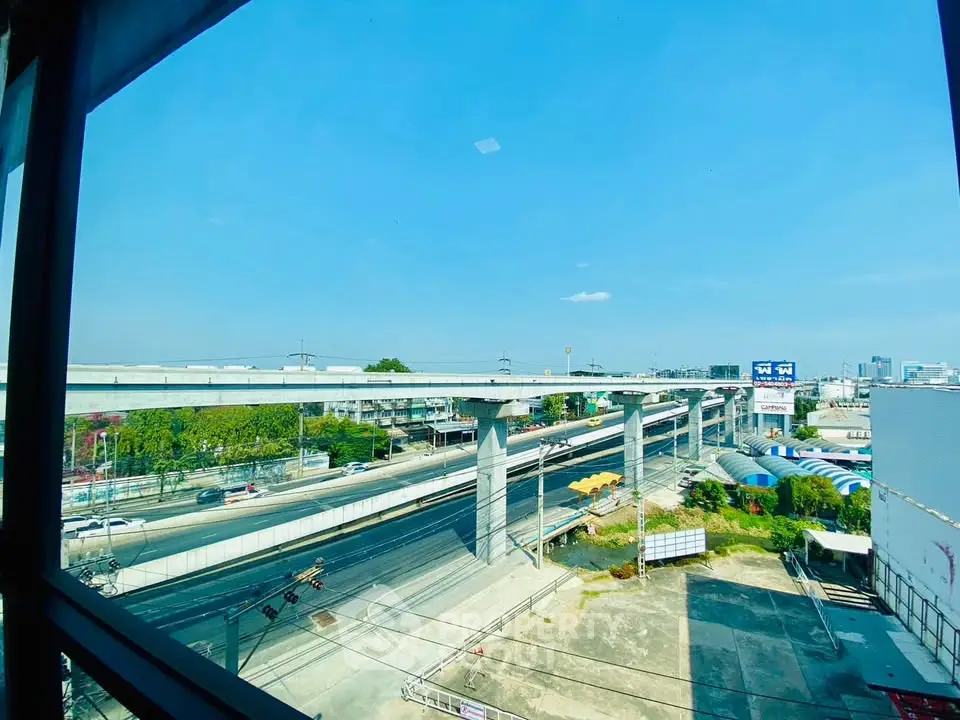 Stunning urban view from high-rise window showcasing elevated highways and cityscape under clear blue sky.