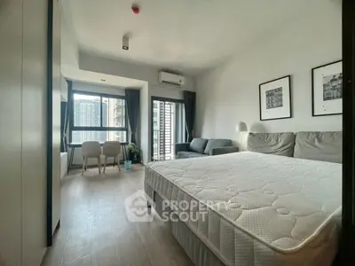 Modern studio apartment with large windows and city view, featuring a cozy bed and stylish decor.