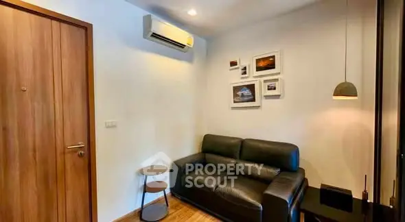 Cozy living room with black leather sofa, modern decor, and air conditioning unit.
