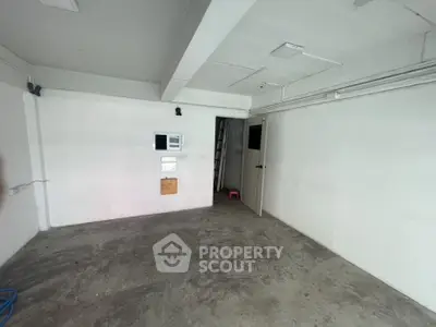 Spacious empty room with concrete floor and white walls, ideal for storage or renovation.
