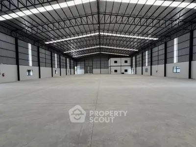 Spacious industrial warehouse with high ceilings and ample natural light, perfect for storage or manufacturing.
