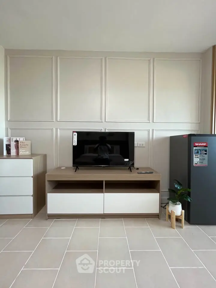 Modern living room with sleek TV stand and refrigerator, showcasing minimalist design and neutral tones.