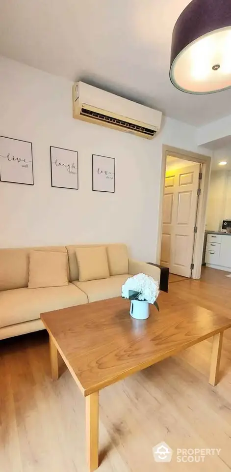 Cozy living room with beige sofa, wooden coffee table, and wall art in modern apartment.