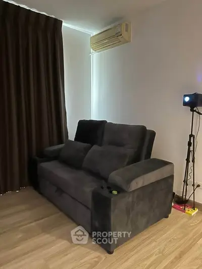 Cozy living room with plush dark sofa and modern projector setup.