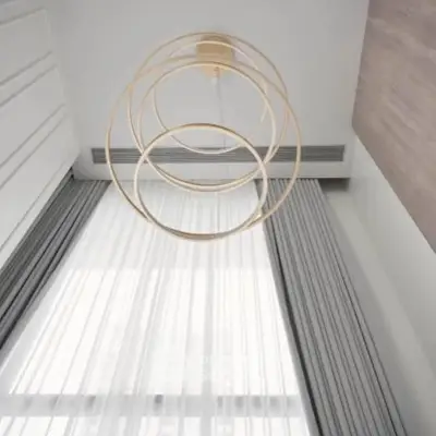 Modern interior with elegant circular chandelier and tall curtains in a stylish living space.