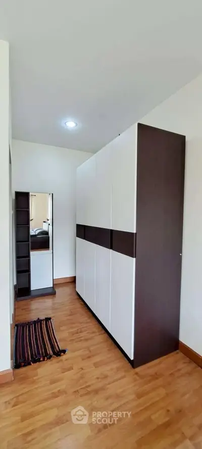 Spacious bedroom with modern wardrobe and wooden flooring