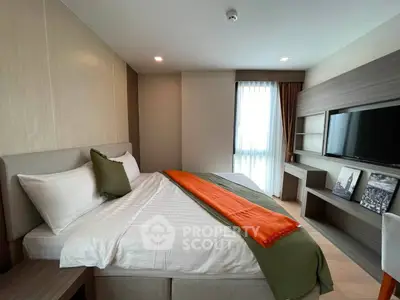 Modern bedroom with stylish decor and natural light, featuring a cozy bed and wall-mounted TV.