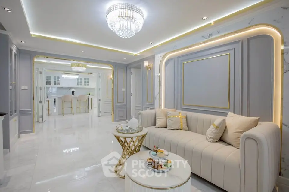 Luxurious living room with elegant decor and open kitchen layout, featuring a stunning chandelier and plush seating.