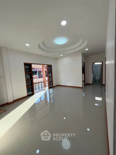 Spacious living room with glossy tiled floors and modern ceiling design, perfect for family gatherings.