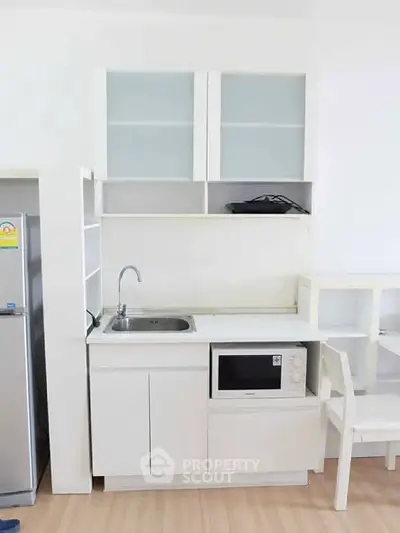 Compact modern kitchen with white cabinetry and built-in microwave