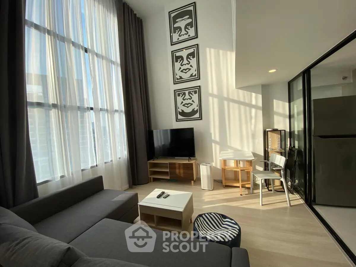 Modern living room with high ceilings, large windows, and stylish decor in a contemporary apartment.